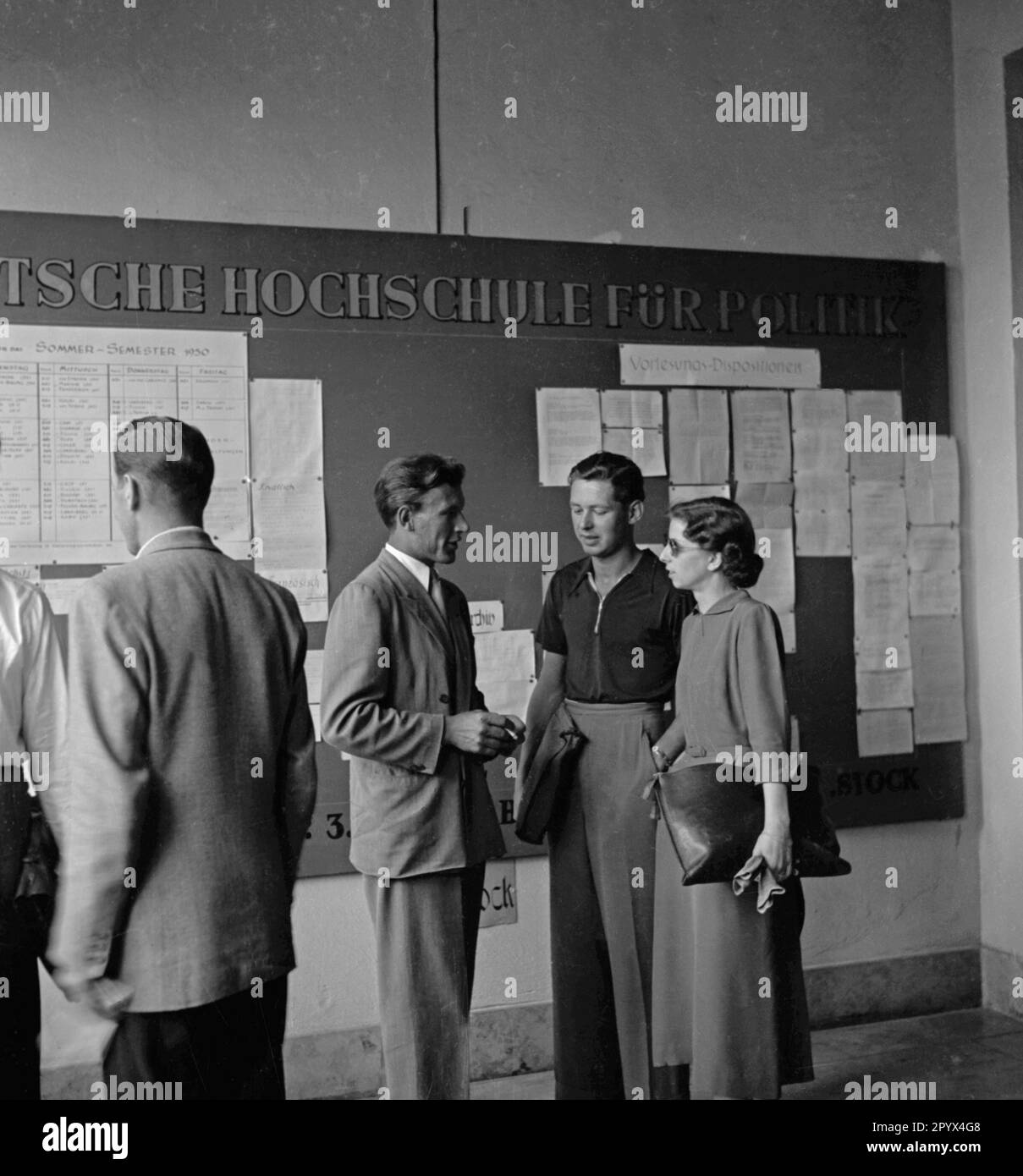 Photo of a group of students in front of the bulletin board of the German Academy for Politics (DHfP) with announcements for the summer semester 1950 in West Berlin. Stock Photo
