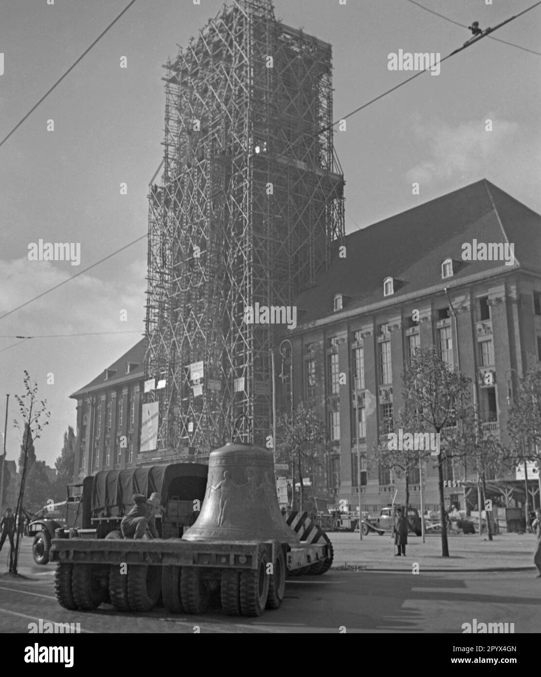 Photo of the Freedom Bell on the back of a low loader of the US Army on Rathausplatz shortly before its installation in the tower of the seat of the Governing Mayor of Berlin, Ernst Reuter (1948-1953) on October 21, 1950. In the background, construction workers in front of the partially destroyed facade of the building. On the scaffolding a poster of the American occupation forces (inscription: Emergency Programme of Berlin with European Recovery Program). The bell sounded for the first time at the ceremony on the United Nations Day (UN) on 24 October Stock Photo