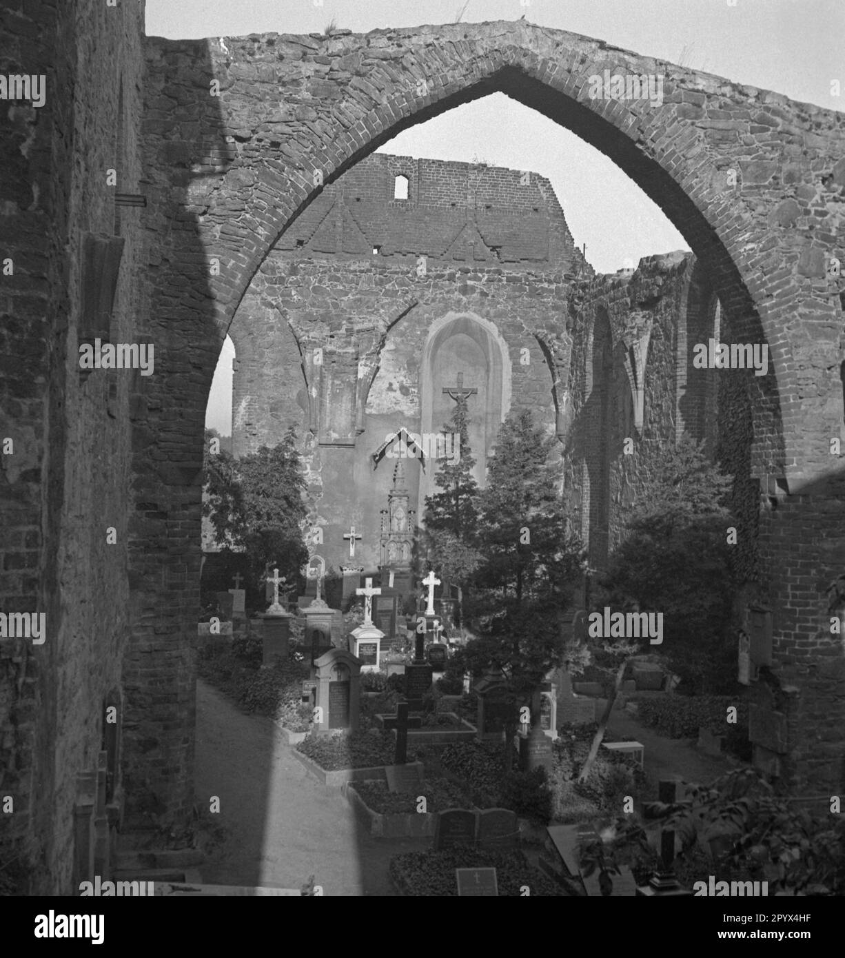 Undated photo of a small burial ground in the ruins of St. Nicolai Church (Upper Sorbian: Miklavsk) in Bautzen (Upper Sorbian: Budysin) in Upper Lusatia, a former Soviet occupation zone (SBZ, today Free State of Saxony). There are graves on the ground and on the wall. All around, the outlines of the nave. Above, a Gothic arch. Stock Photo