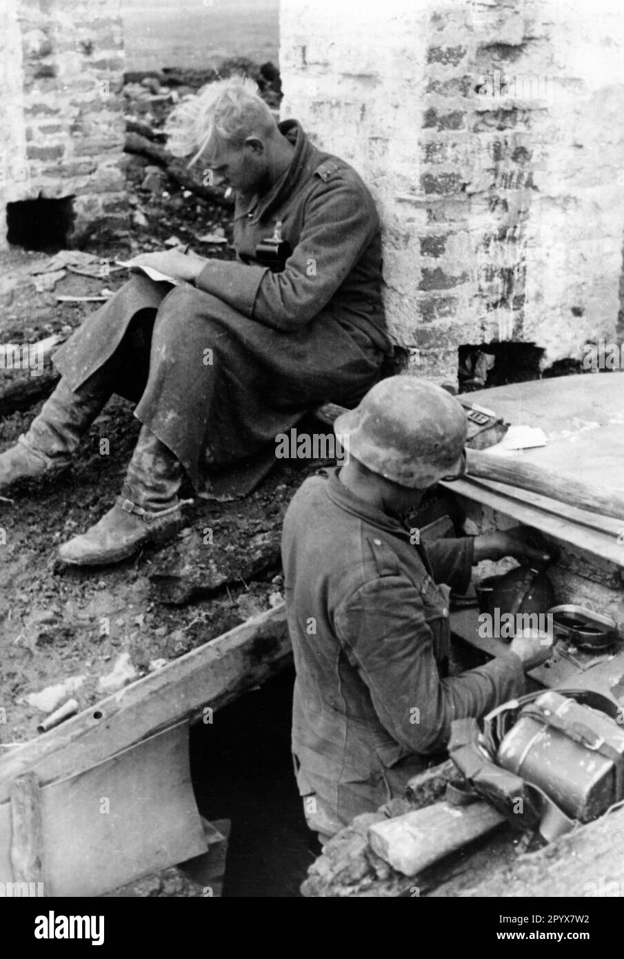 Soldiers prepare food in their position on the Eastern Front, the one on the left writes a letter. Photo: Schuerer. [automated translation] Stock Photo