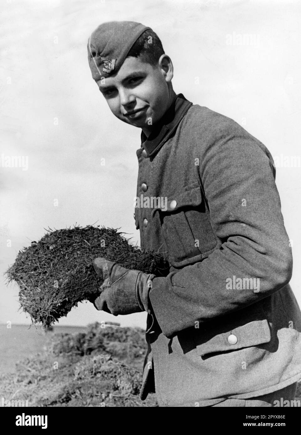 Young member of the Reich Labor Service on one of the British Channel Islands laying turf on a field airfield. Photo: Schwahn. [automated translation] Stock Photo
