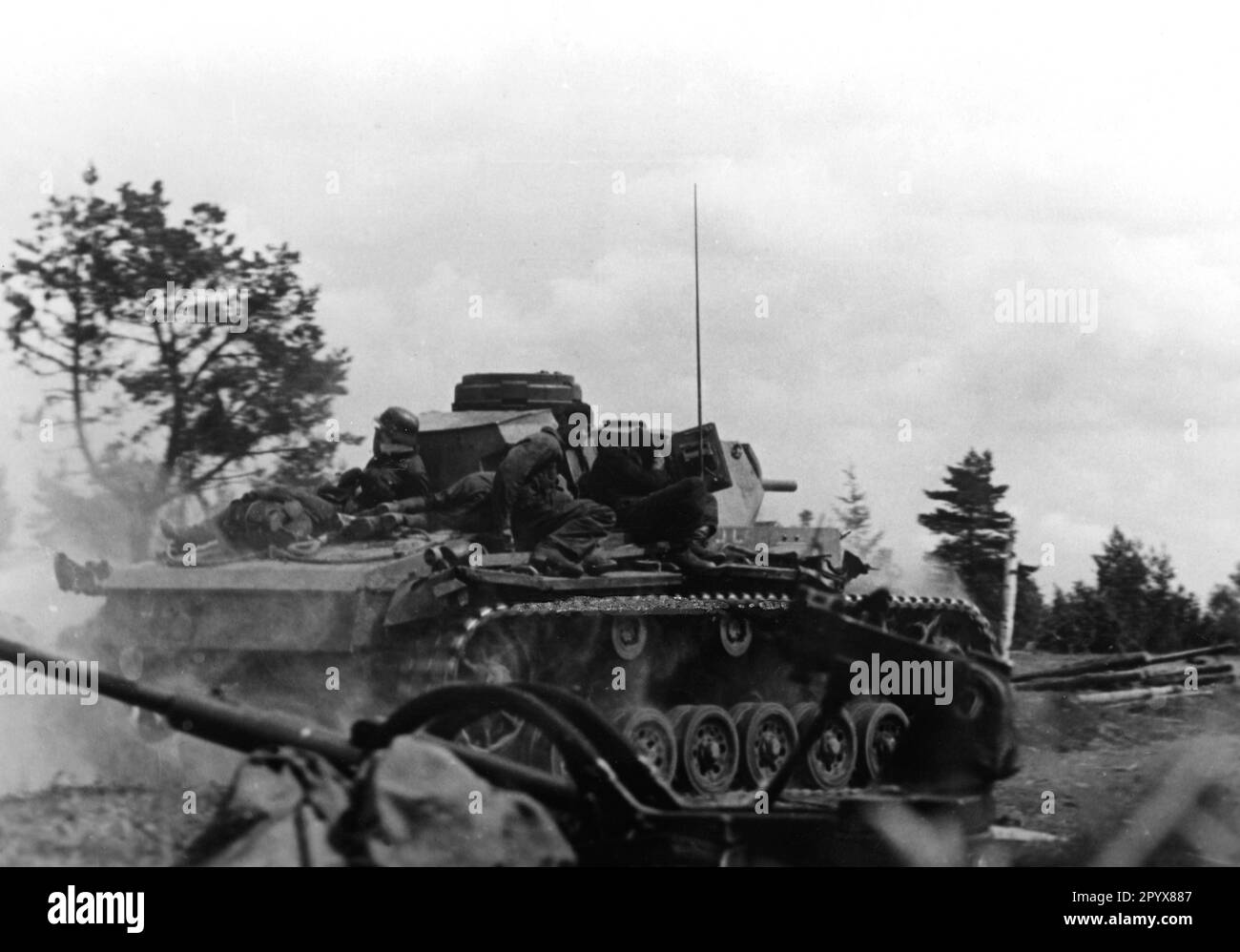 A Panzer III of a Waffen SS unit rolls forward with mounted infantrymen ...