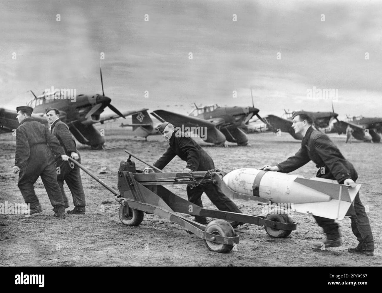 'Junkers Ju 87 ''Stuka'' of the Sturzkampfgeschwader 165 in Kitzingen near Würzburg. Ground crew transports a bomb to the parked aircraft. [automated translation]' Stock Photo