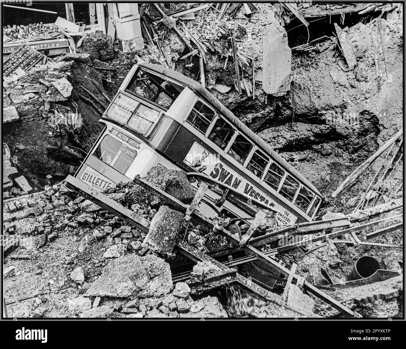 WW2 The London Blitz with a London bus in a bomb crater after a terror bombing blitz by Nazi Germany. The aftermath of a bombing raid, a bus lies in a crater in Balham, South London. Air Raid Damage in Britain during the Second World War. World War II Stock Photo