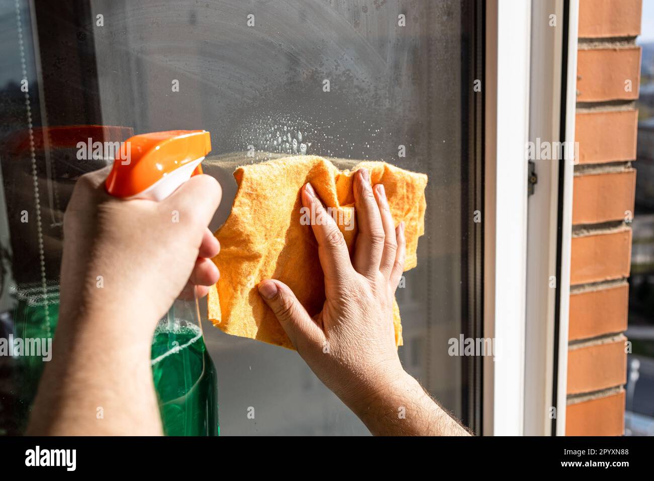 cleaning outdoor home window glass with spray and rag in urban house ...
