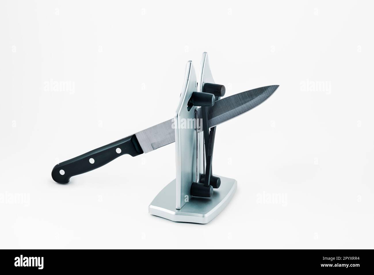 a kitchen knife in a desktop knife sharpener, on a white background Stock Photo