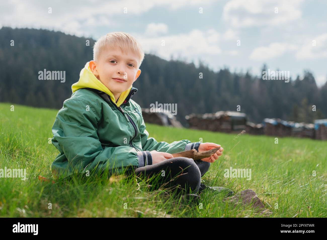 Fun teenager sits on hillside. Boy resting in mountains. School boy
