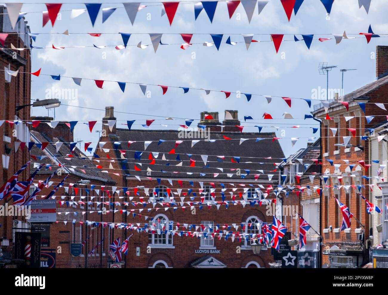 Celebrations in the Warwickshire town of Alcester, UK ready for the Coronation of King Charles III.  Flags and bunting adorn the high street. Stock Photo