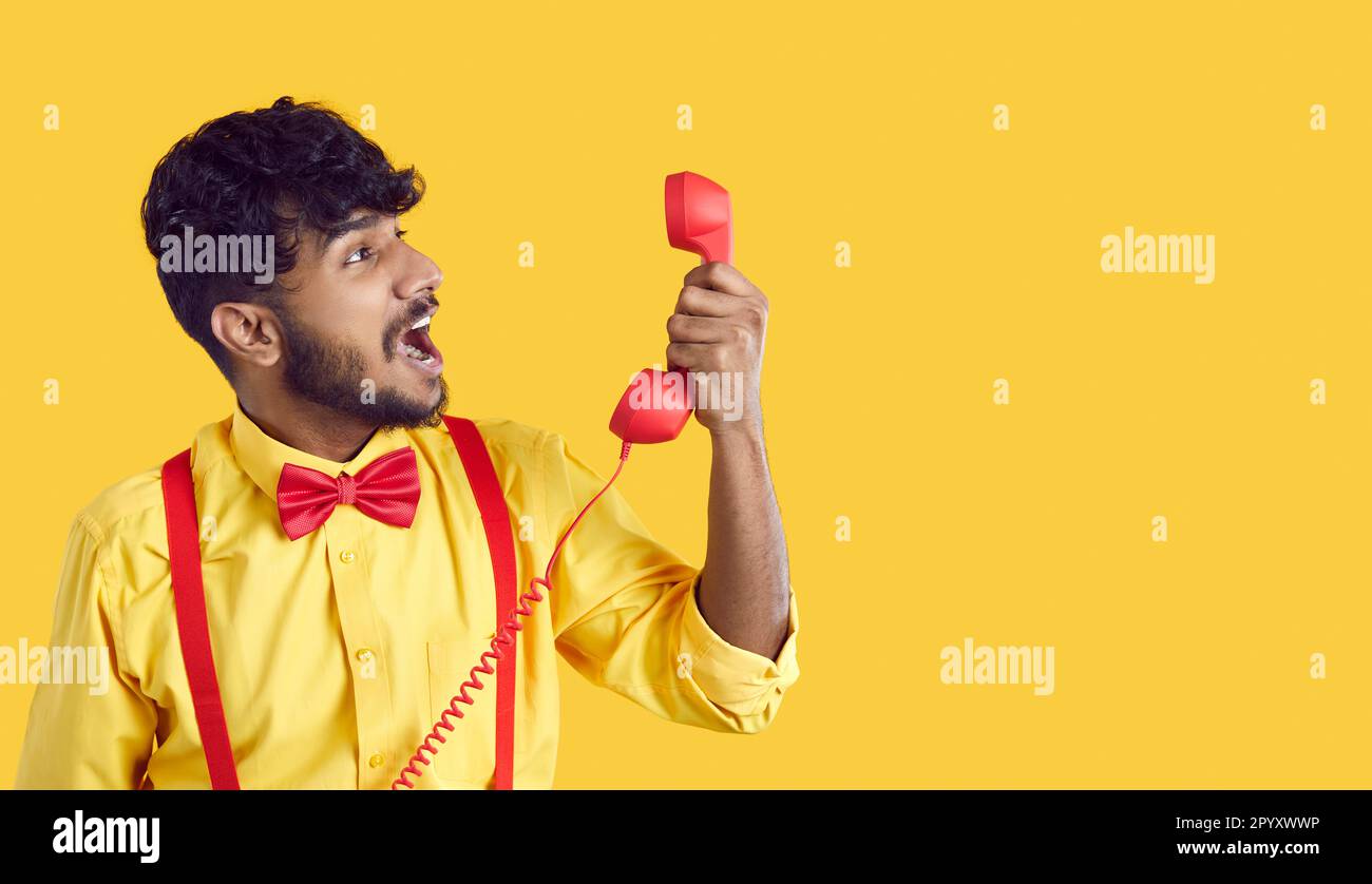 Young South Asian man shouting loudly holding landline phone nervous when making support call Stock Photo