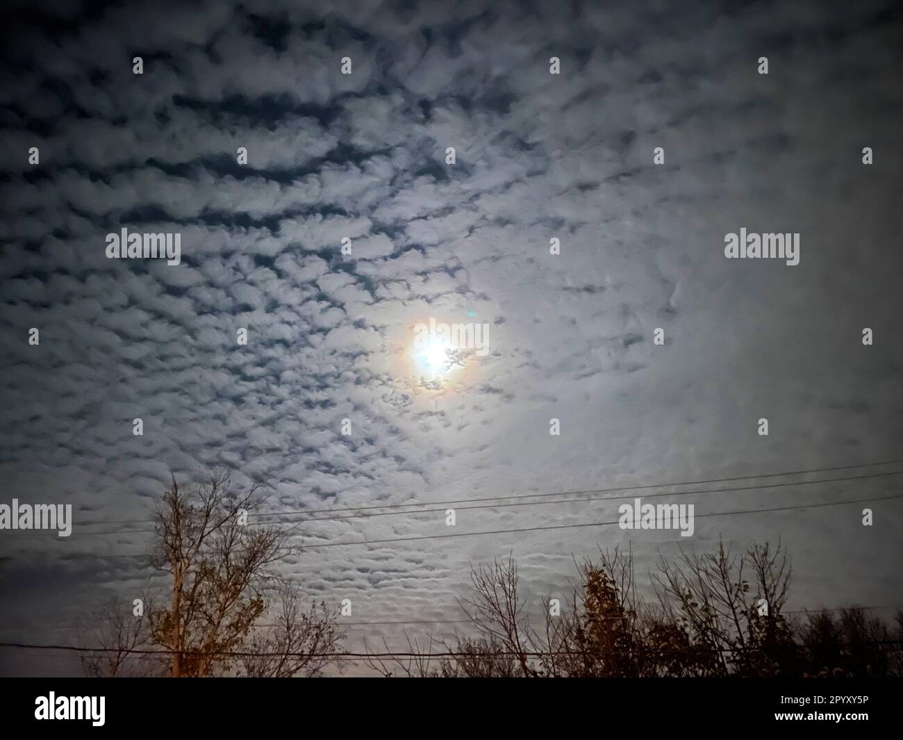 A bright moon shining through a mackerel sky. Stock Photo