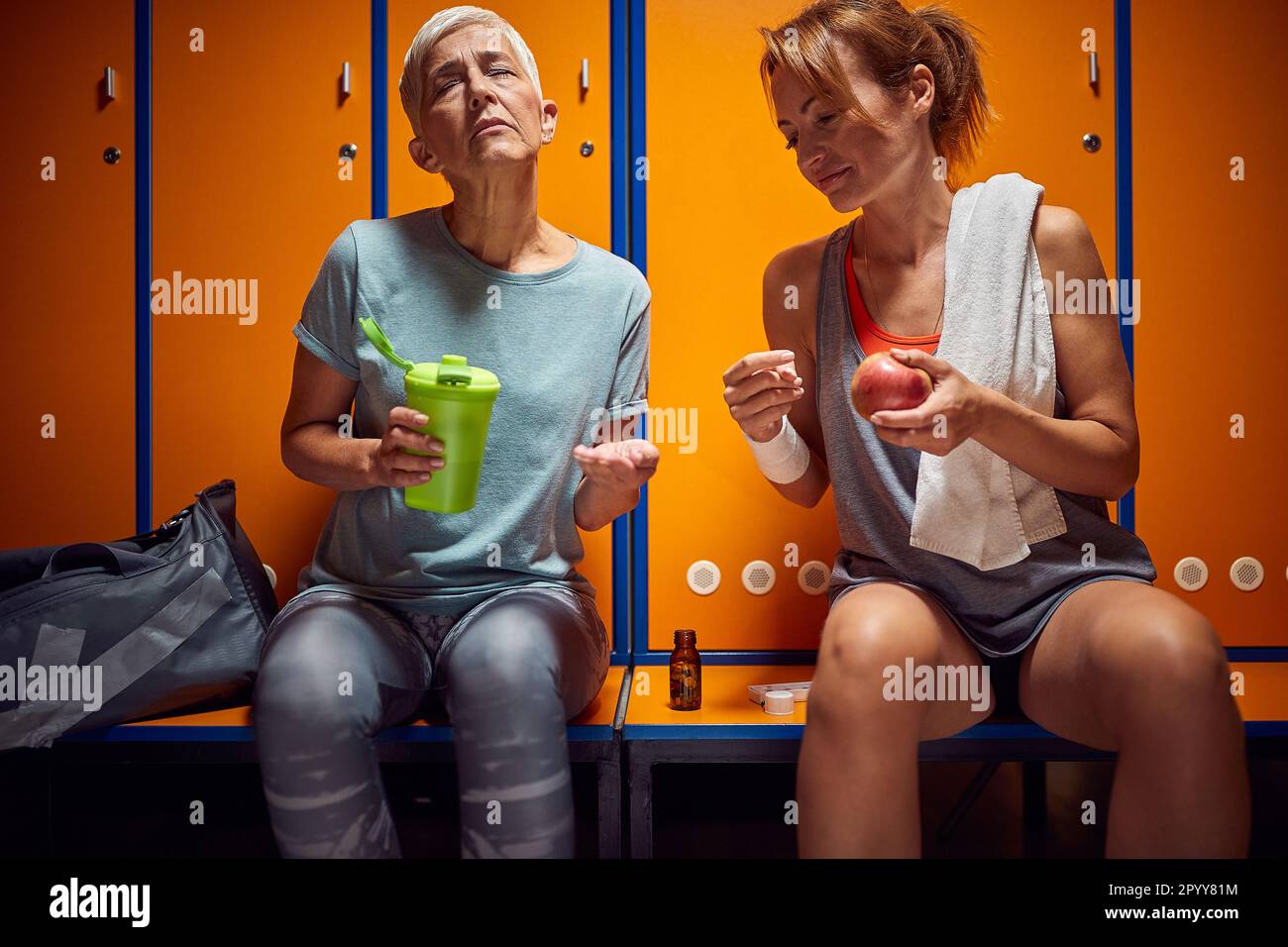 Senior woman sitting in dressing room, feeling unwell, young woman sitting by her side helping her get better. Senior life concept. Stock Photo