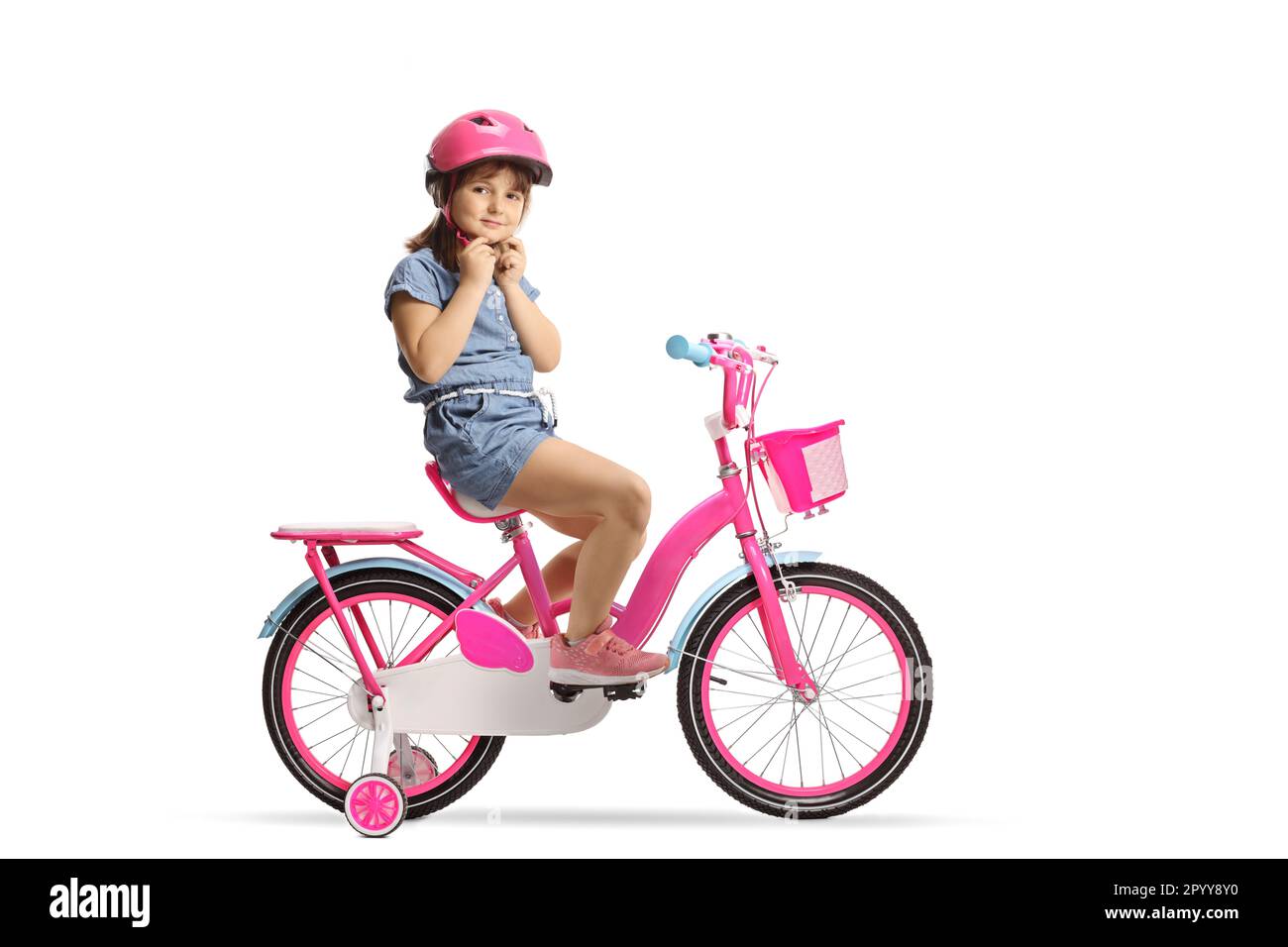 Little girl putting on a helmet and sitting on a bicycle with training
