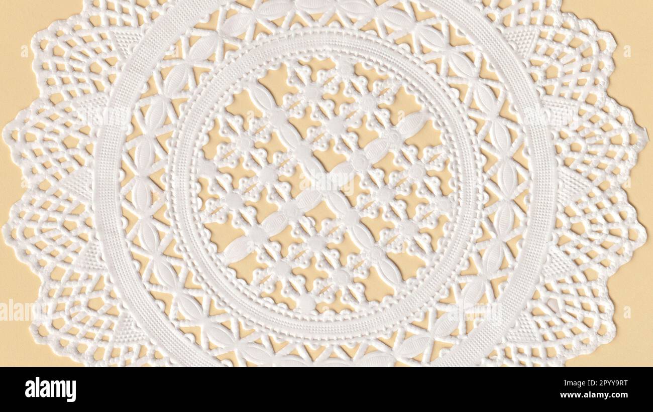 Part of a paper Cup Cake Doily on top of a yellow paper. Stock Photo