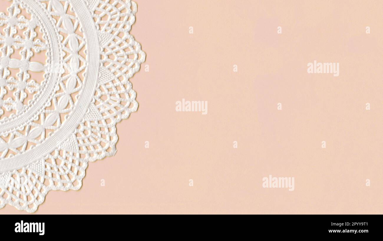 Part of a paper Cup Cake Doily on top of a pink paper. With space for your own text Stock Photo