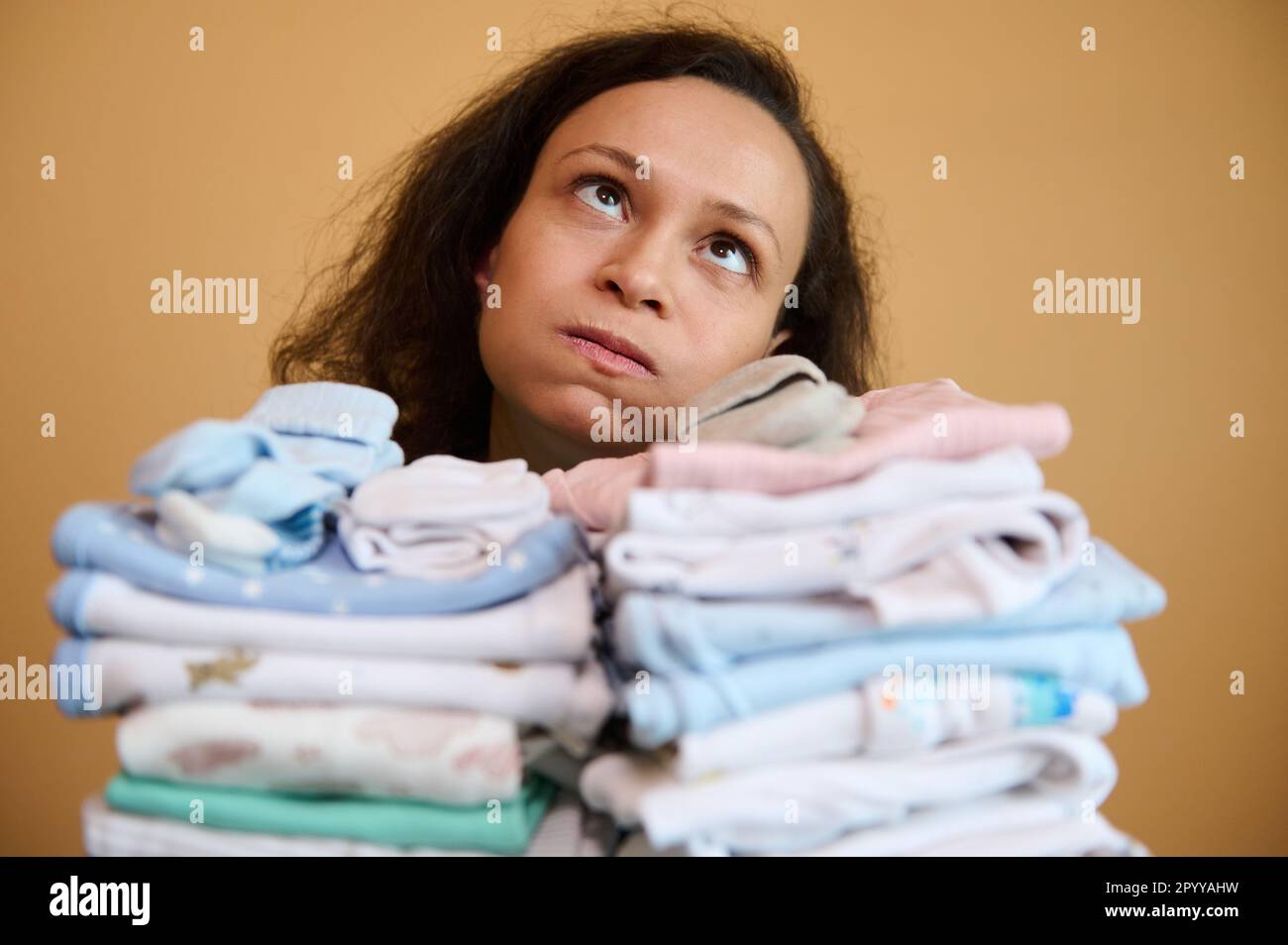 Headshot young mother holding up a stack of washed, ironed baby clothes