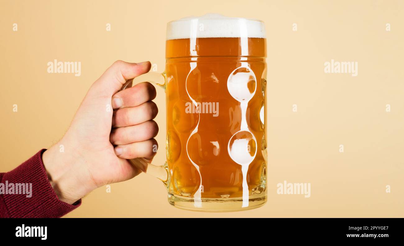 Man's hand holding mug of beer. Bavarian beer. Oktoberfest festival. Fresh cold beer in glass. Male hand with full beer glass. Hand with pint of craft Stock Photo