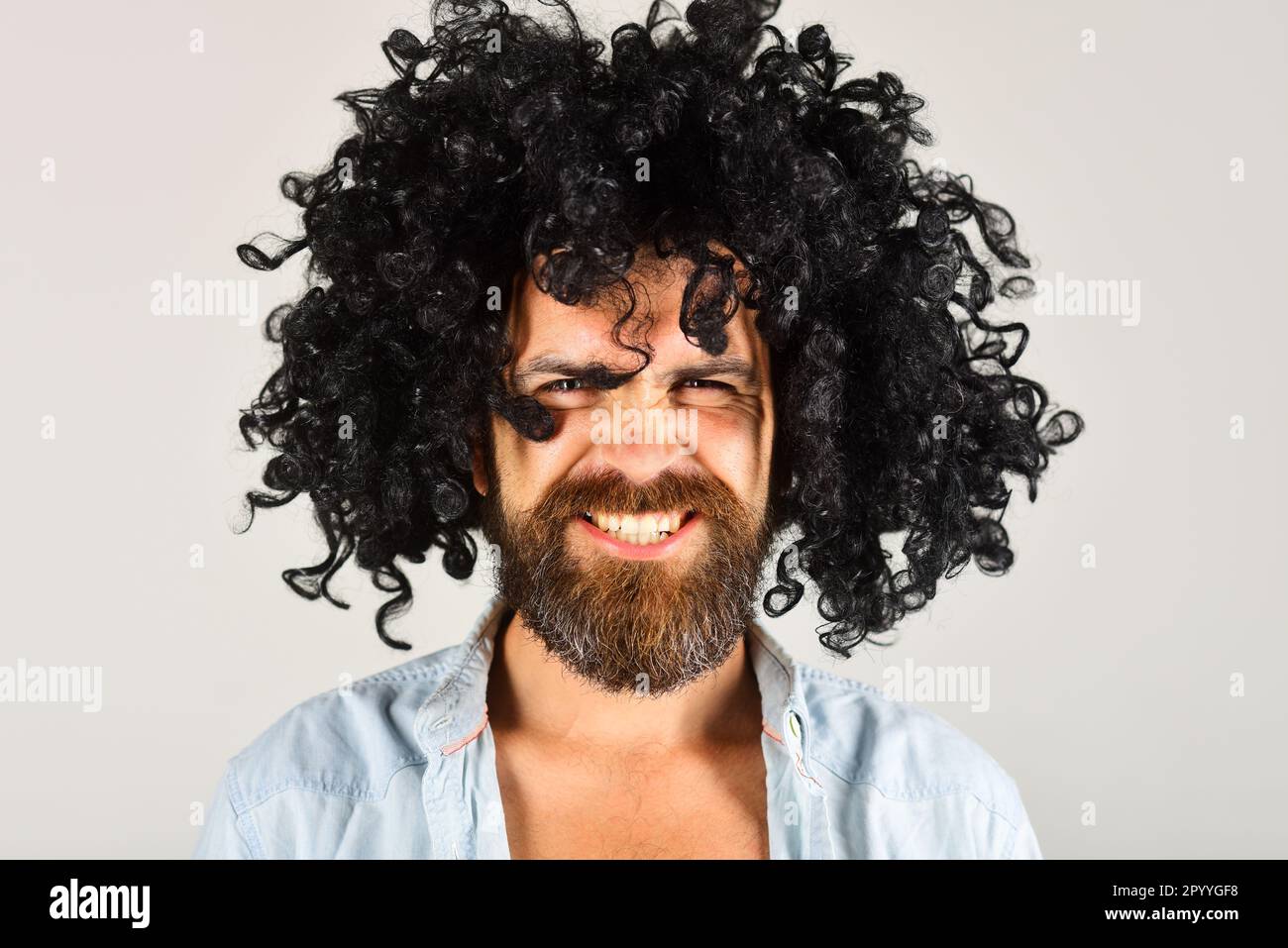 Bearded man in black wig. Angry man with beard and mustache in curly wig. Bearded hipster in black curly afro wig. Male in periwig. Party time. Barber Stock Photo