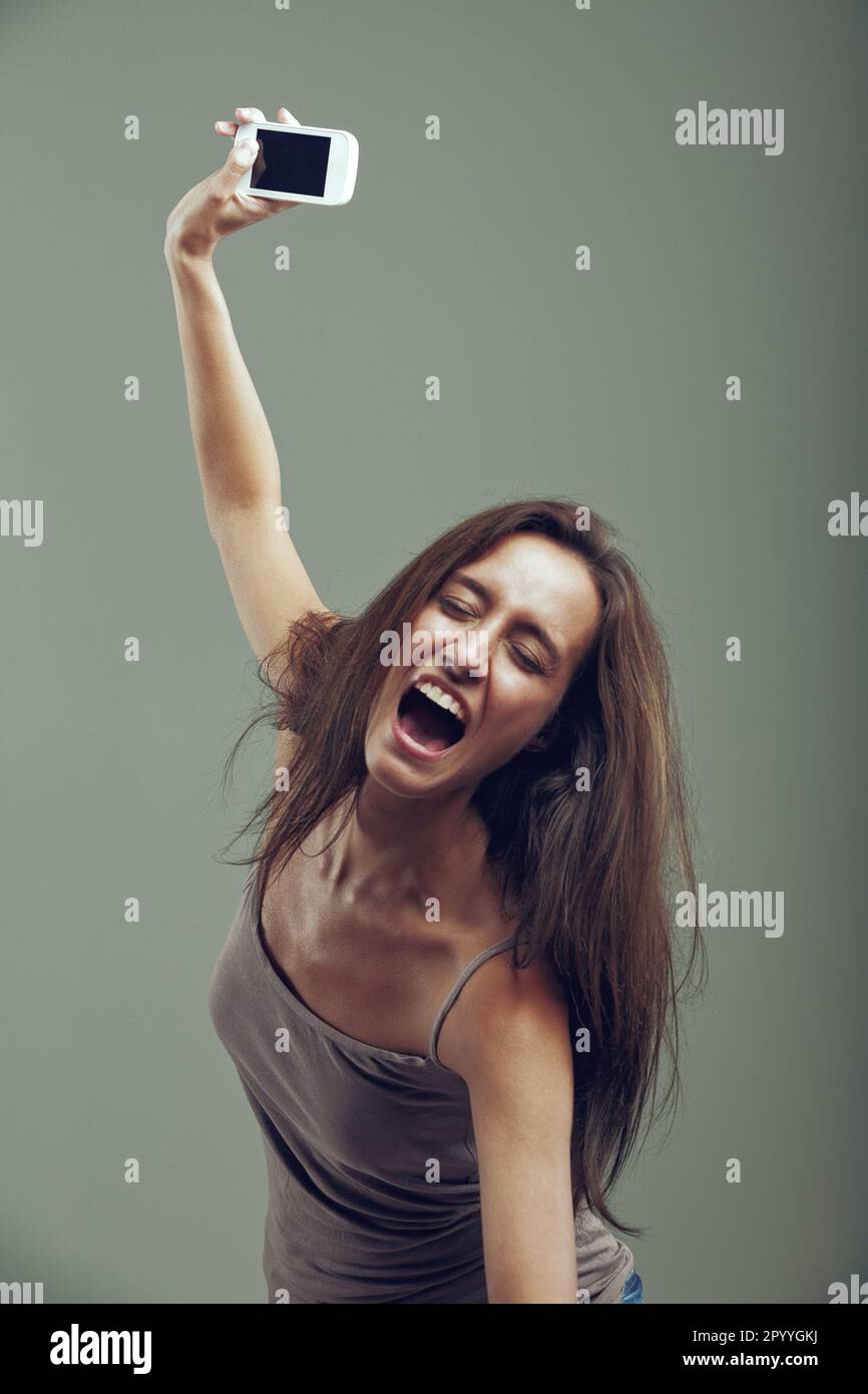 With an athletic leap, a woman throws her cell phone away. Revitalized by anger, she has violent strength and accompanies the gesture with a furious s Stock Photo
