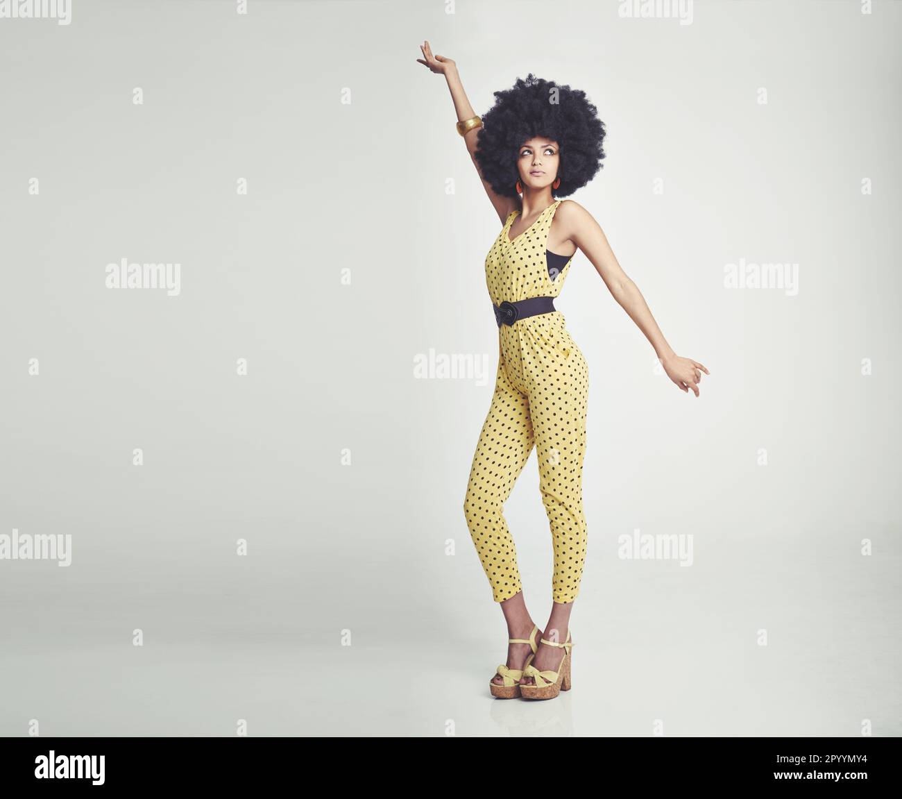 Lets disco. A young woman wearing a 70s retro jumpsuit and striking a ...