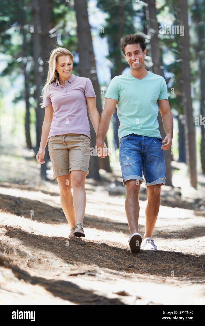 Taking a nature stroll. A happy young couple walking hand in hand in ...