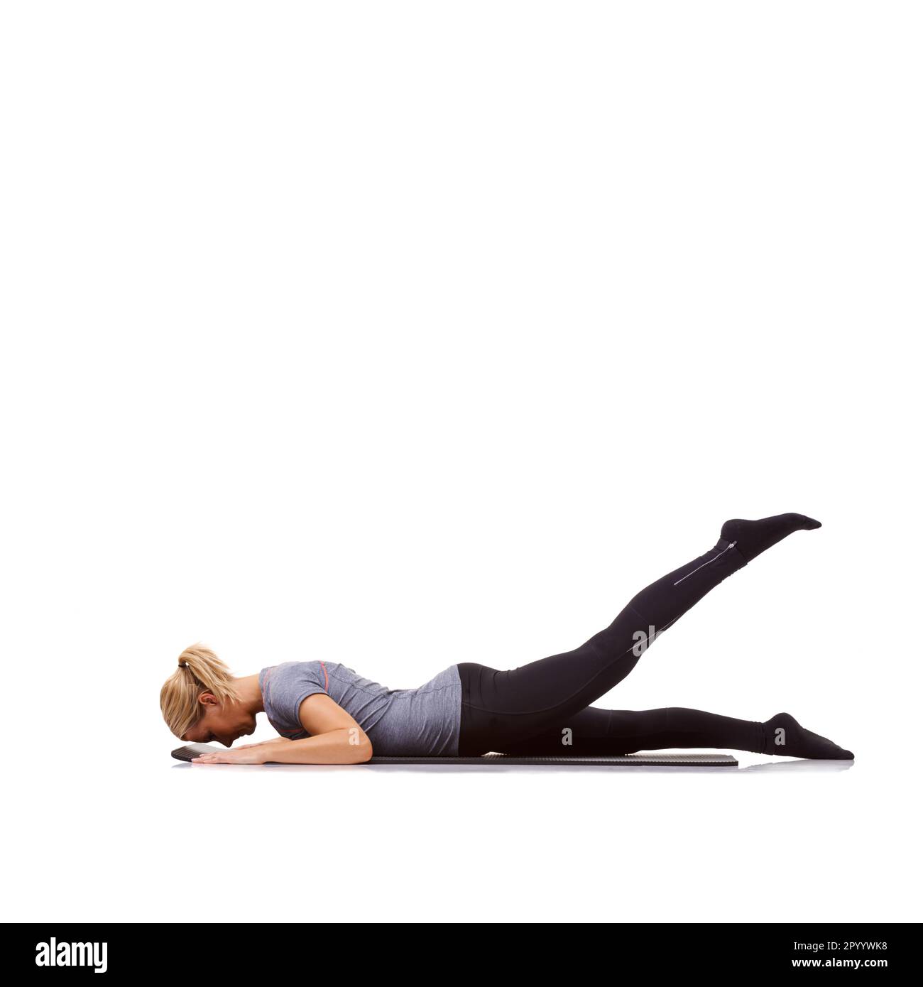 Leg lifts. A fit young woman working out on her exercise mat against a
