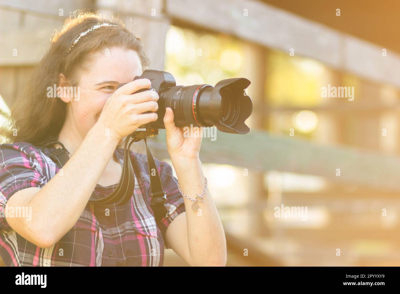 Happy young australian female photographer with DSLR camera taking photos in rural setting Stock Photo