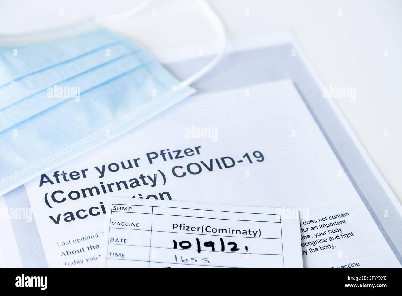 After your Pfizer (Comirnaty) COVID-19 Vaccination information sheet and medical mask Stock Photo