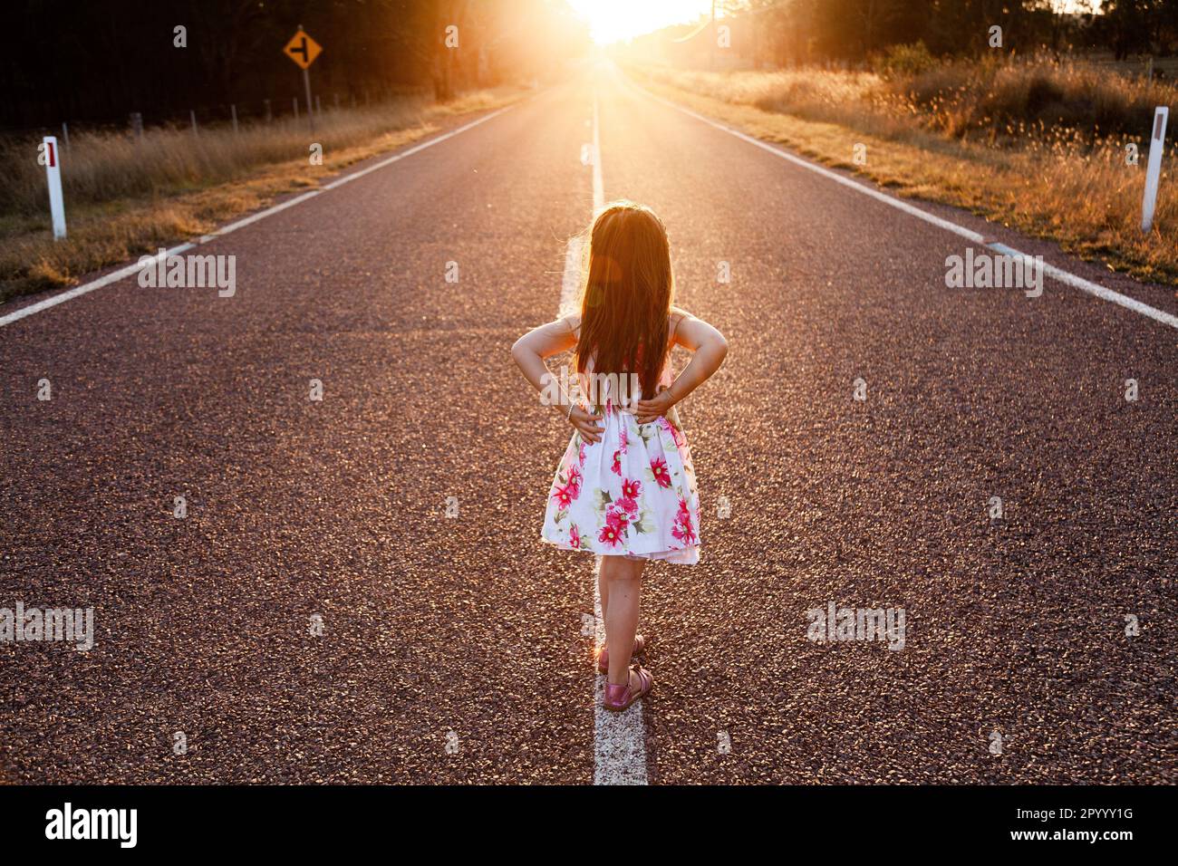 young girl walking down country road at sunset Stock Photo Alamy