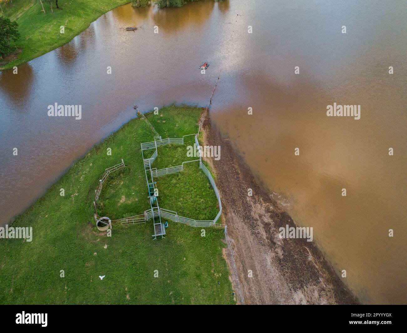 Floodwaters on farmland creeping towards cattle yards seen from aerial view Stock Photo