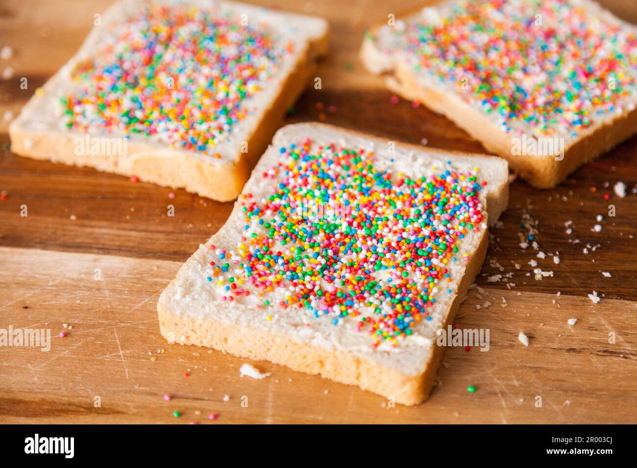 making fairy bread with hundreds and thousands on white buttered bread Stock Photo