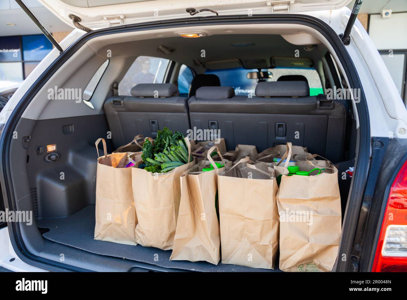 brown paper bags in boot of car full of grocery shopping from direct to