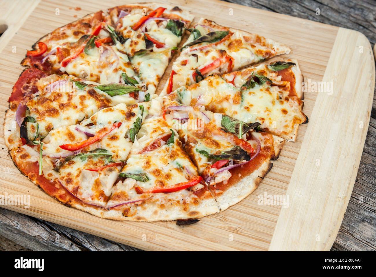 Fresh home made pizza from outdoor pizza oven on serving board Stock Photo