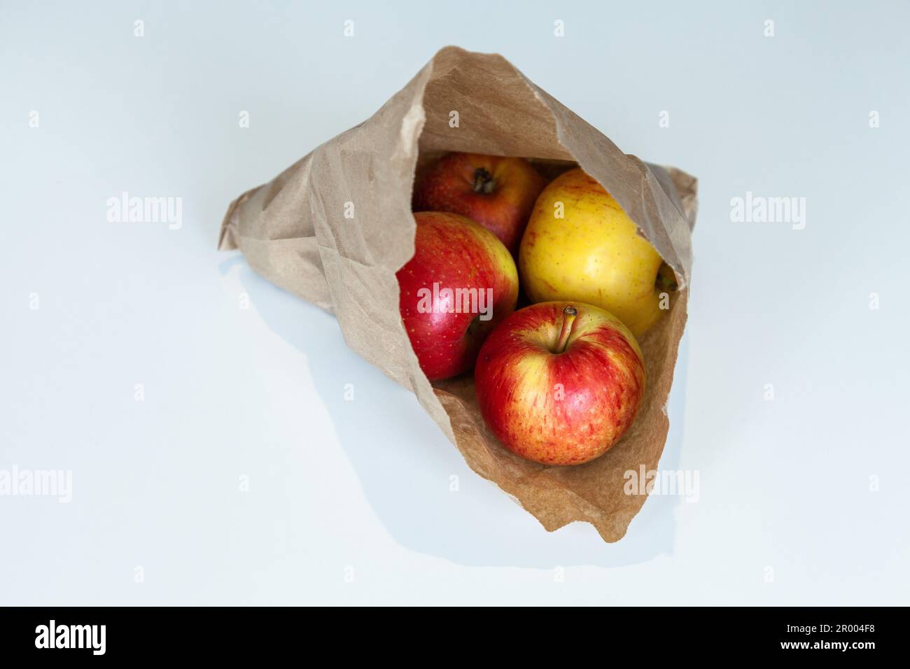Small organic apples in brown paper bag on white table Stock Photo