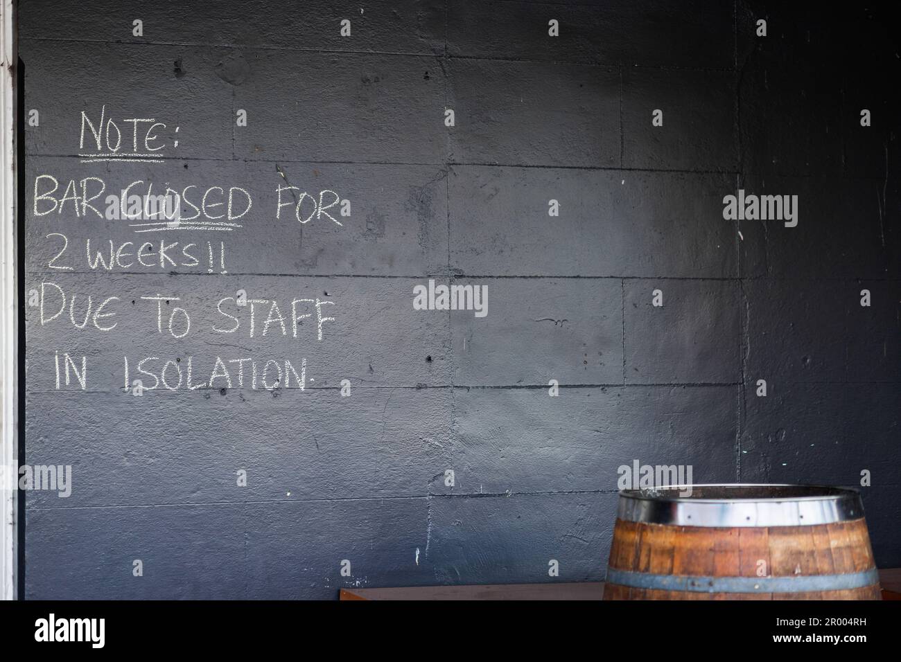 chalk writing on wall of pub building Note: bar closed for 2 weeks due to staff in isolation Stock Photo