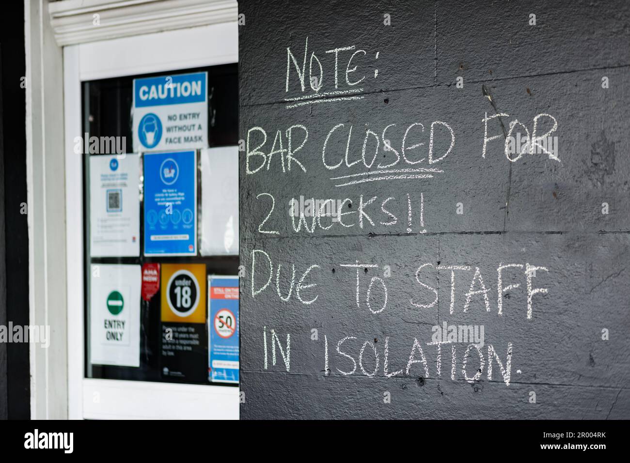 chalk writing on wall of pub building Note: bar closed for 2 weeks due to staff in isolation Stock Photo