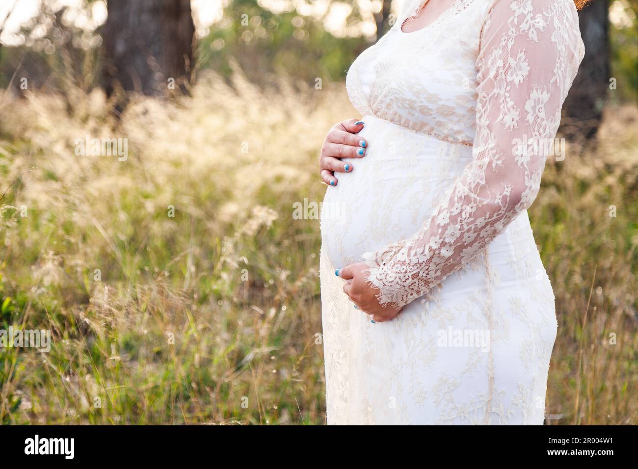 Expectant mother with hands on her belly in australian paddock Stock Photo