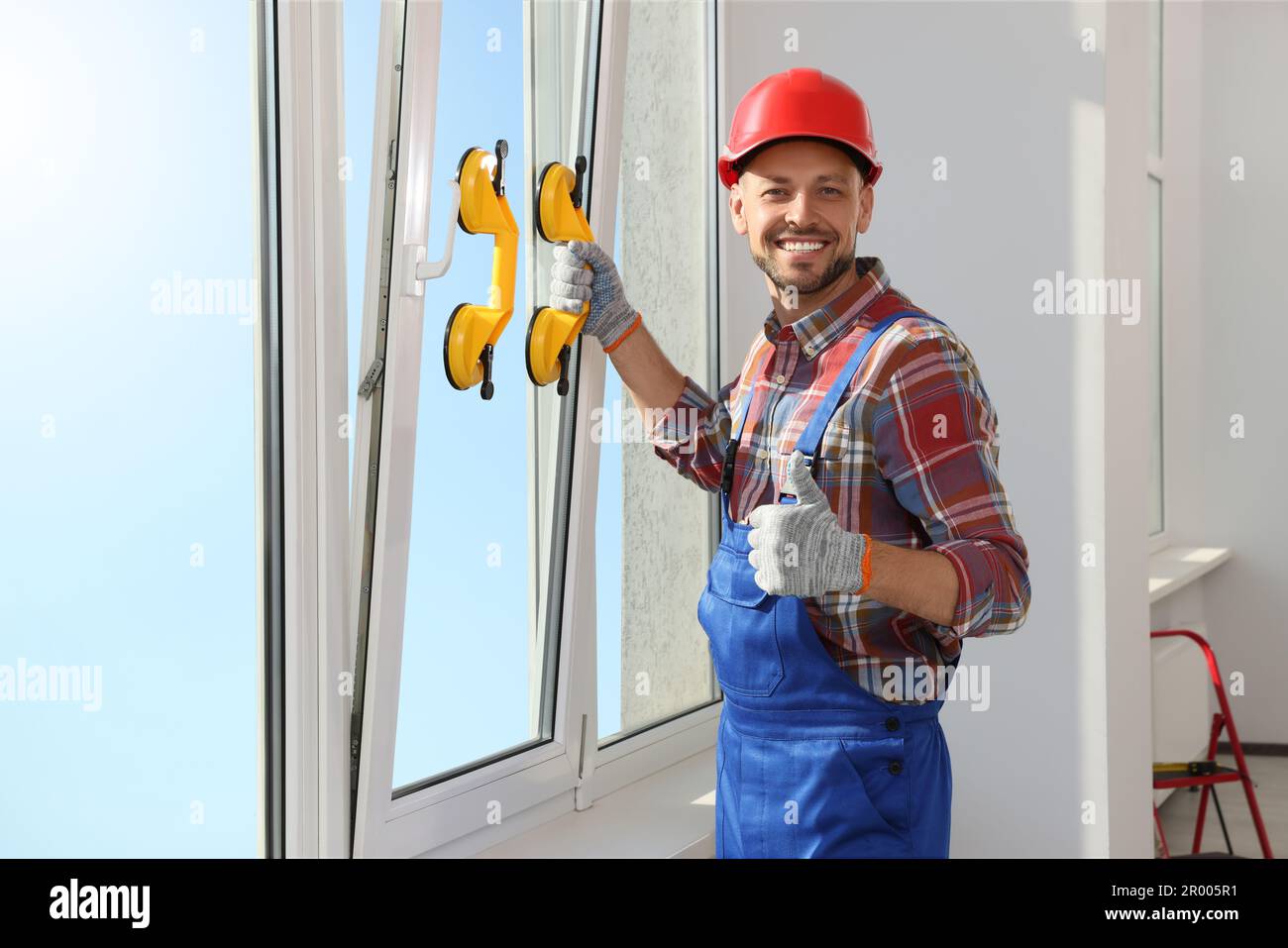 Worker using suction lifters during plastic window installation indoors Stock Photo