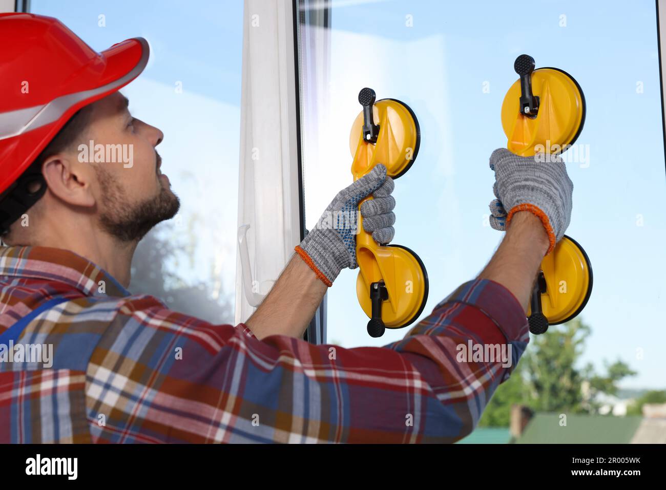 Worker using suction lifters during plastic window installation indoors Stock Photo