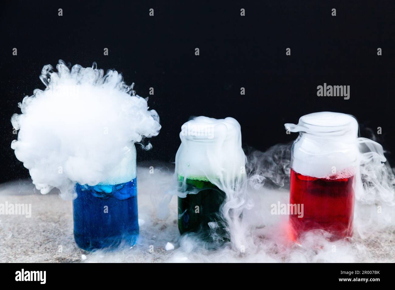 Fun science experiment with dry ice and coloured water and detergent on black backdrop Stock Photo