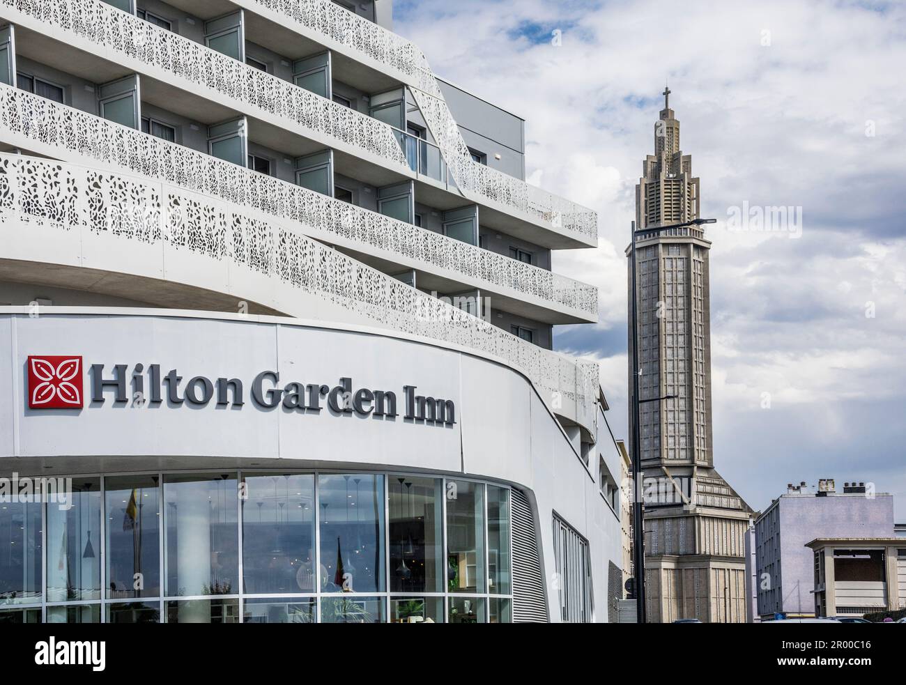 the facade of the Hilton Garden Inn against the backdrop of the monumental concrete tower of St. Joseph's Church, Le Havre, Seine-Maritime, Normandy, Stock Photo