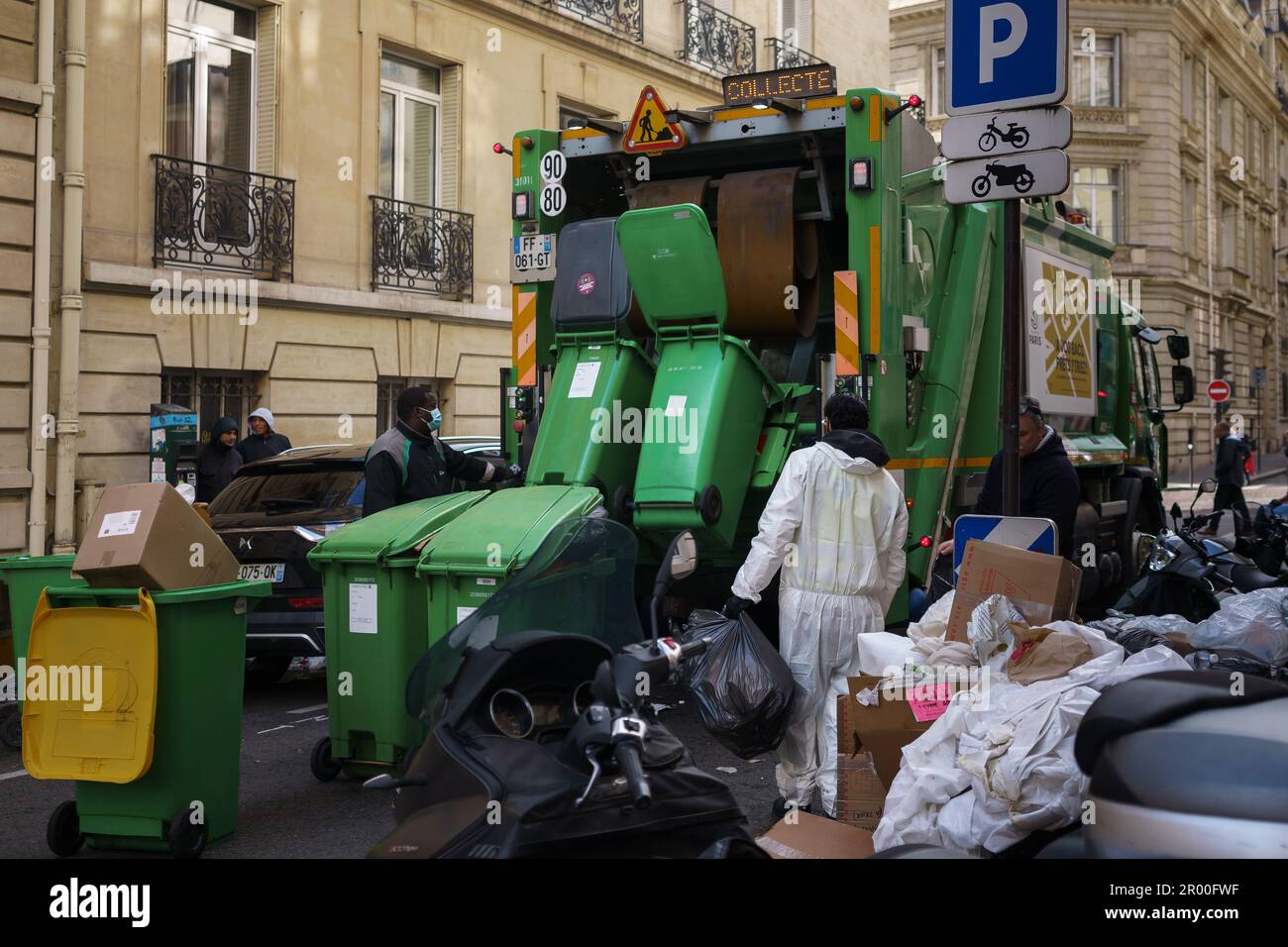 Garbage men collecting trash in the streets of Paris, France. March 25