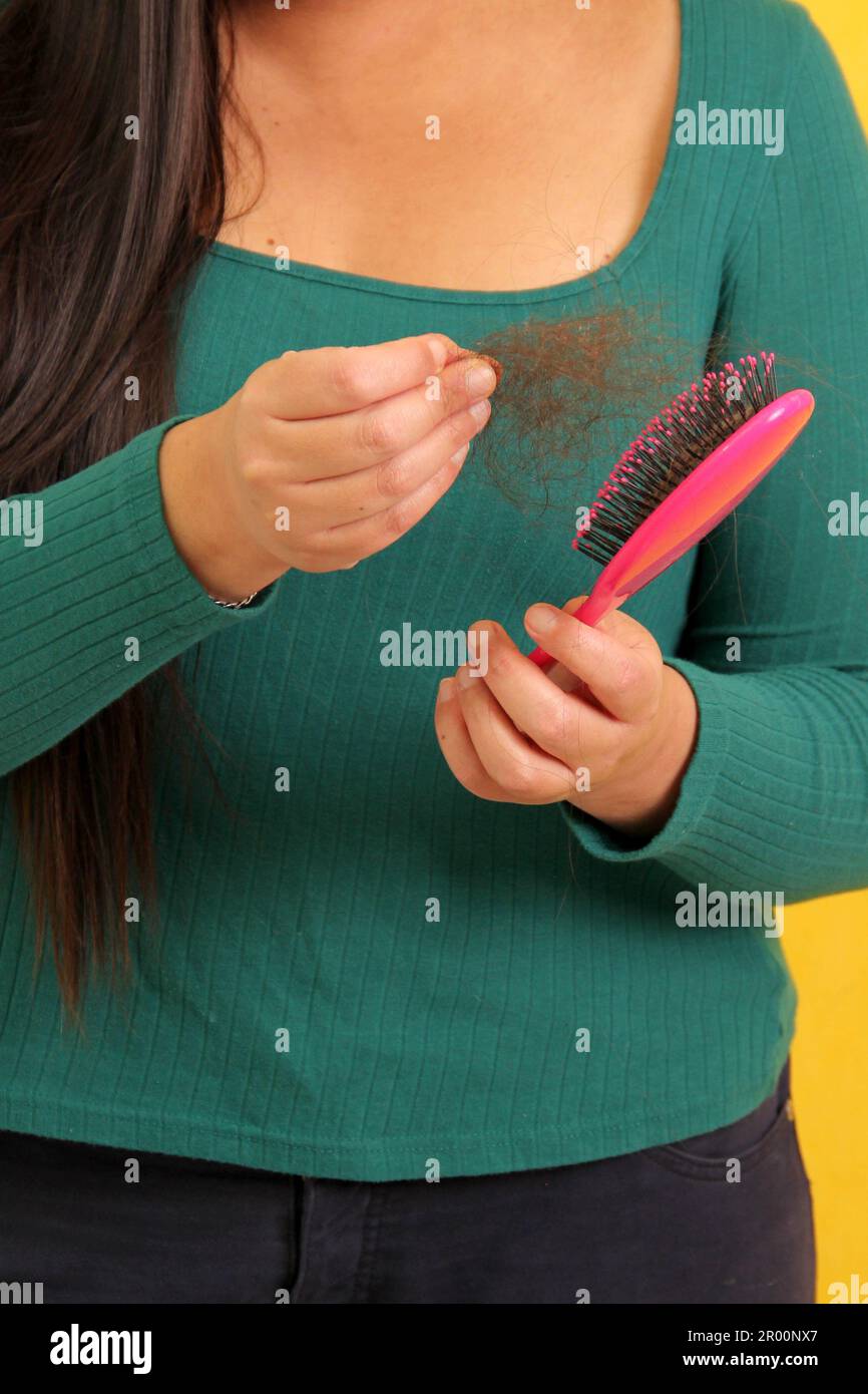 Woman's hands take a hairbrush with many fallen hairs after brushing