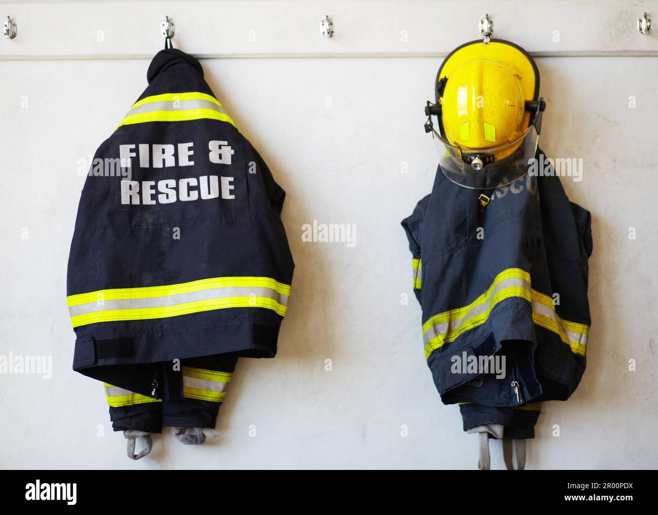 Firefighter, uniform and clothing hanging on wall rack at station for