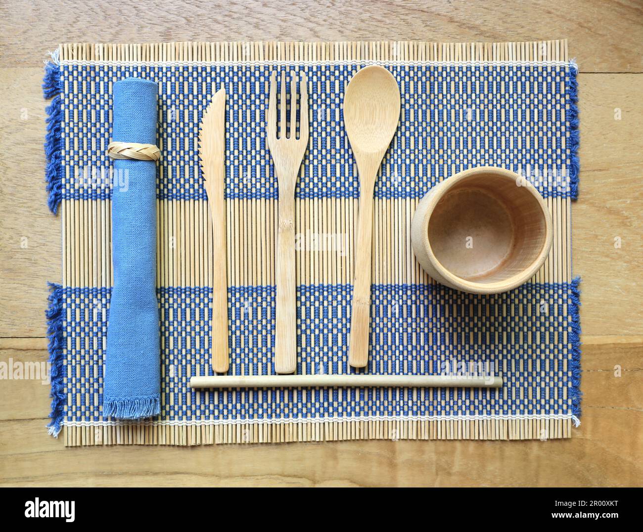 Bamboo wood cutlery, disposable fork, spoon,knife, straw and bamboo cup made of natural material on placemat Stock Photo
