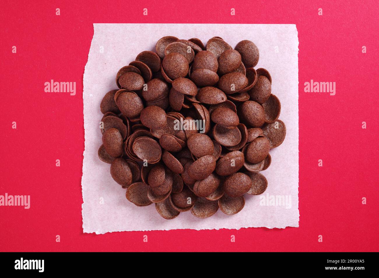 Chocolate cereals breakfast on red background. Glazed shells. Top view Stock Photo