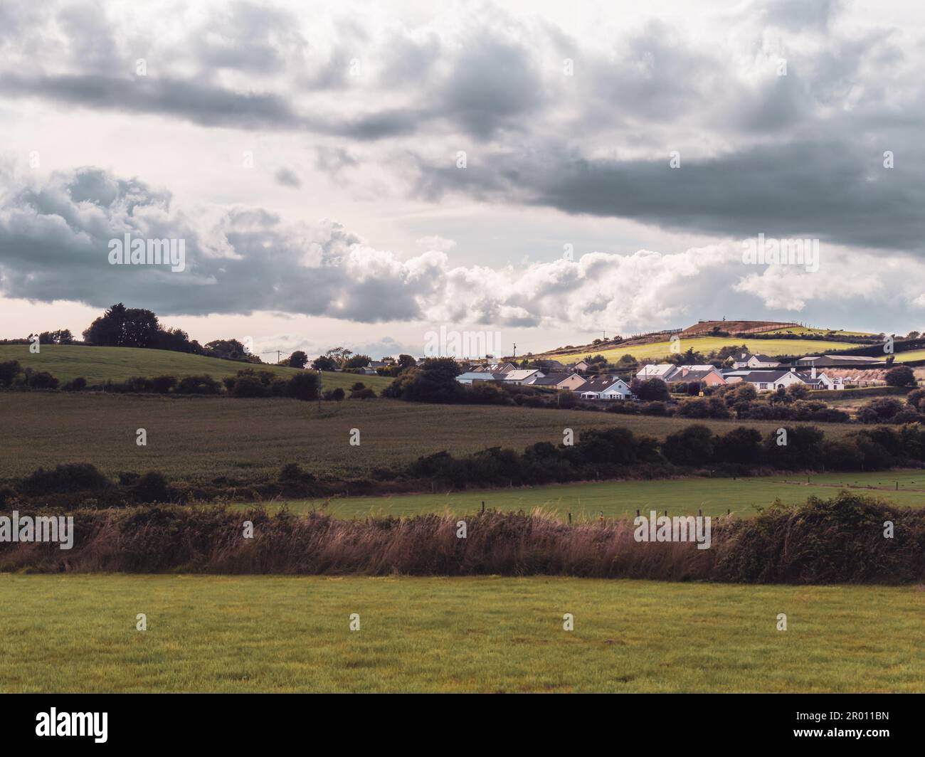 cumulus clouds over a small Irish village on a summer evening. Irish settlement in County Cork, dramatic landscape. European countryside, rustic lands Stock Photo