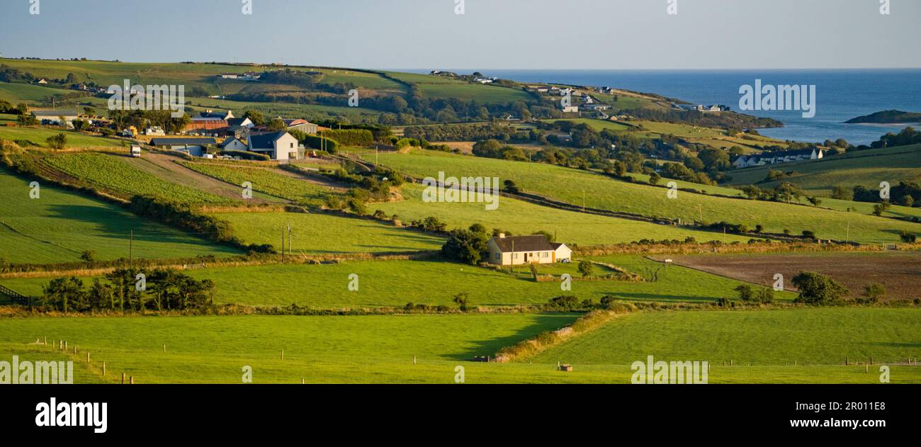 farm fields in the Ireland on a summer evening. Agricultural Irish landscape. Pastures for livestock, house on green grass field. Stock Photo