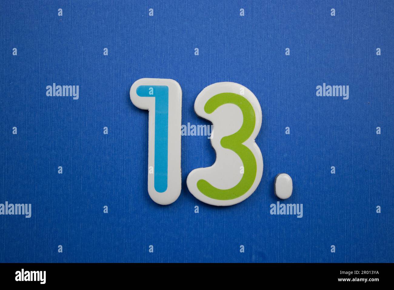 The number 13, placed on a blue background, photographed from above, in light blue and green