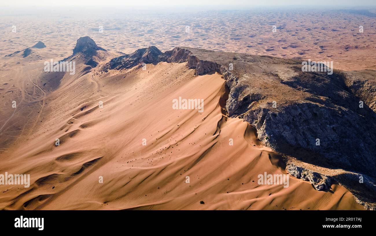 Aerial panorama of Fossil Rock in the Sharjah desert of the United Arab Emirates. Sand meeting the rocky mountain in the UAE desert Stock Photo