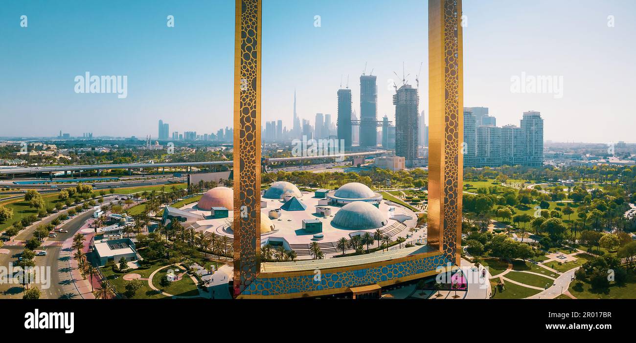 Dubai skyline seen through the large golden frame with nearby park and Dubai skyline aerial cityscape view of the Emirate Stock Photo